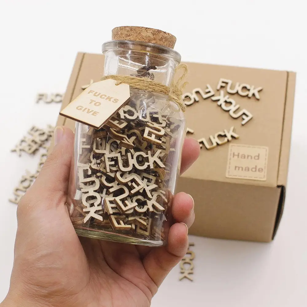 Glass jar filled with wooden cutouts of the word 'fuck,' labeled 'Fucks to Give,' perfect for humorous gifts or desk decor.