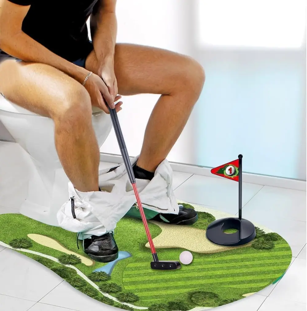 Person sitting on a toilet playing toilet golf with a mini putting green, golf club, ball, and flag, perfect for bathroom fun and gag gifts.